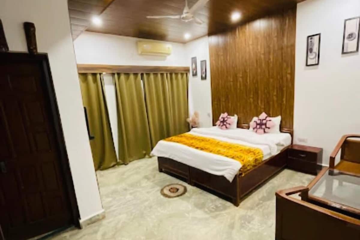 A bedroom with a bed, a wooden headboard, a nightstand, a desk, and a ceiling fan.