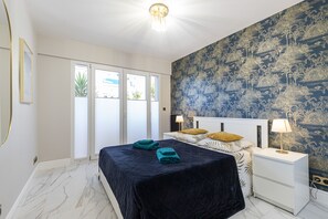Quarto com cama, mesas de cabeceira e uma janela grande.