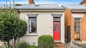 A two-story house with a red door, a small window, and a mailbox. - Explore South Hobart Village from an 1855 Cottage (Dynnyrne)