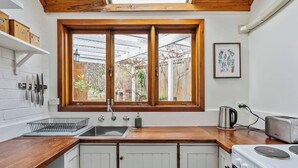 A compact kitchen with a wooden countertop, a double sink, and a stove. - Explore South Hobart Village from an 1855 Cottage (Dynnyrne)