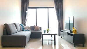 A modern living room with a grey sectional sofa, a coffee table, a TV on a black stand, and a small decorative item on the stand.