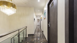 A hotel hallway with a marble floor, a glass railing, and a chandelier. - Hotel Classio Andheri (Mumbai)