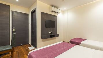 Habitación de hotel con cama, una silla, un televisor montado en la pared y un equipo de aire acondicionado.