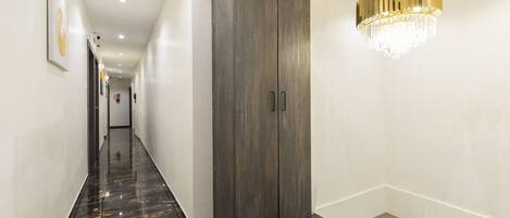 A corridor with a marble floor, a wardrobe, and a chandelier.