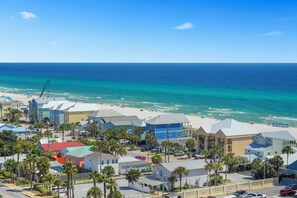 Eine Küstenstadt mit Immobilien direkt am Strand, blauem Himmel und Blick auf den Ozean.