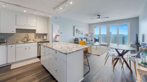 Una cocina moderna con armarios blancos, encimera de granito y comedor con mesa redonda y sillas.