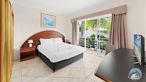 Een hotelkamer met een bed, nachtkastje, televisie en uitzicht op de omgeving.