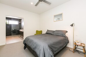 Une chambre à coucher avec un lit, une table de chevet, une lampe et une fenêtre.