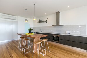 Eine moderne Küche mit einer Holzeile, Barhocker, einem an der Wand aufgehängten Fisch und einem großen Herd.
