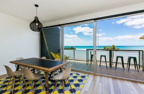 Ein modernes Interieur mit Essbereich, eine große Schiebeglasdoor zu einem Balkon mit Meerblick.