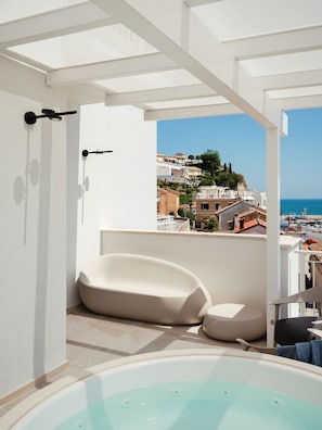 Relax in a spacious bathroom with a bathtub and sleek sink, and enjoy a clear view of the coastal town from the large balcony.