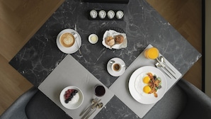 A breakfast setup with croissants, pastries, coffee, eggs, and fruit on a marble table. - View Place & Spa (Numana)
