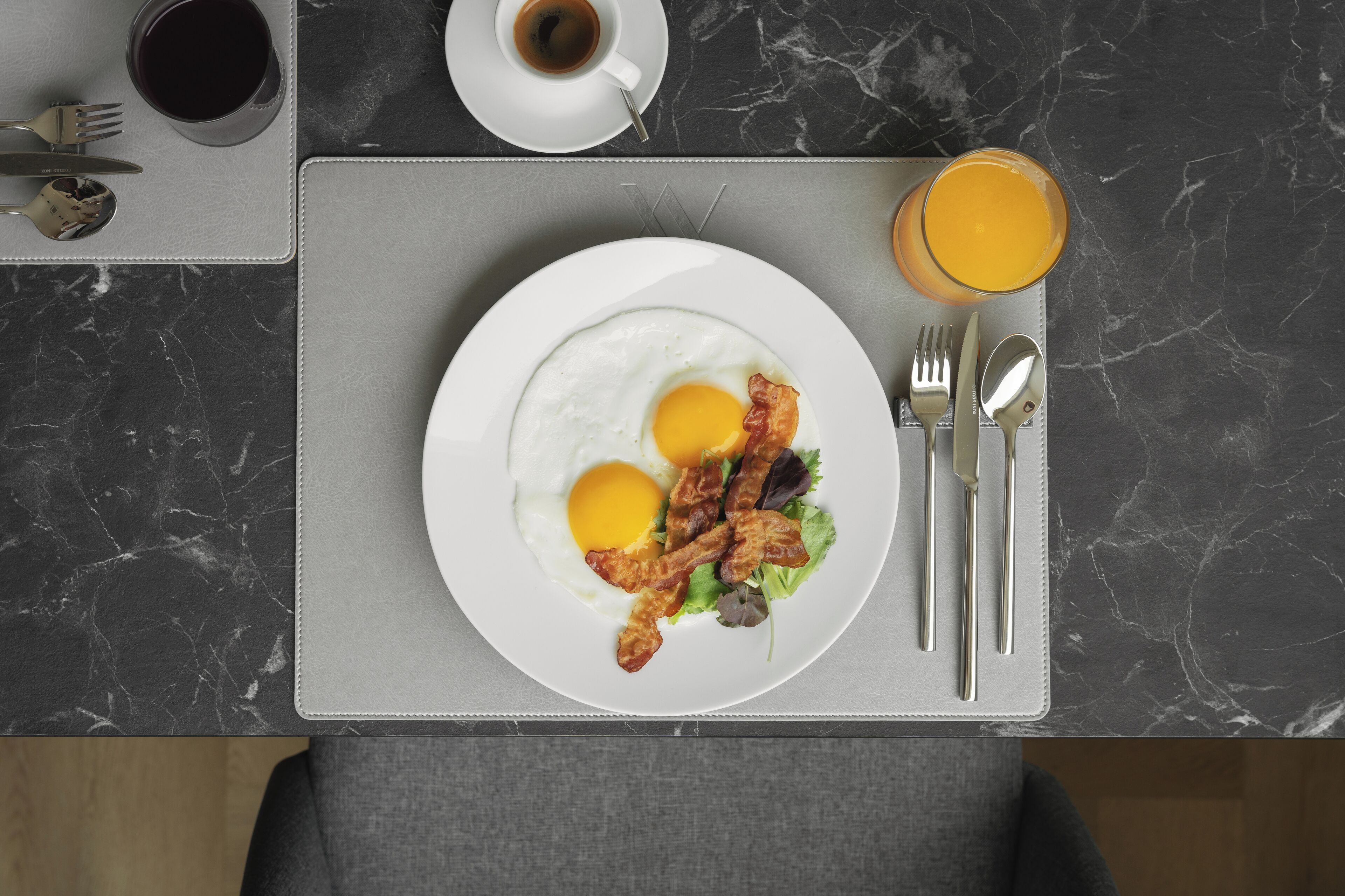 Uma mesa de mármore com um prato de ovos, bacon e vegetais.