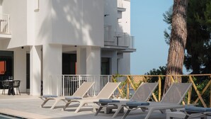 A modern building with a pool, sun loungers, and a dining area. - View Place & Spa (Numana)
