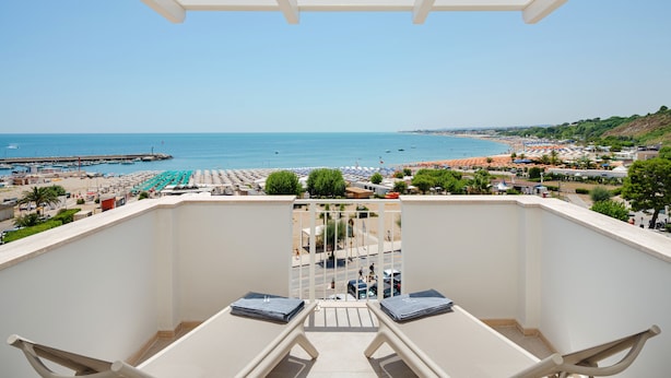 A balcony with a view of a beach, a pier, and a town in the distance. - View Place & Spa (Numana)