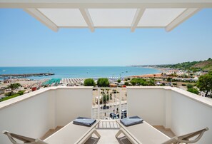 A balcony with a view of a beach, a pier, and a town in the distance. - View Place & Spa (Numana)