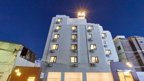 Un edificio de varios pisos con varias ventanas y unidades de aire acondicionado, bajo un cielo nocturno con una fuente de luz brillante en la parte superior.