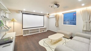 Una sala de estar moderna con una pantalla grande, asientos cómodos y vista a la ciudad.