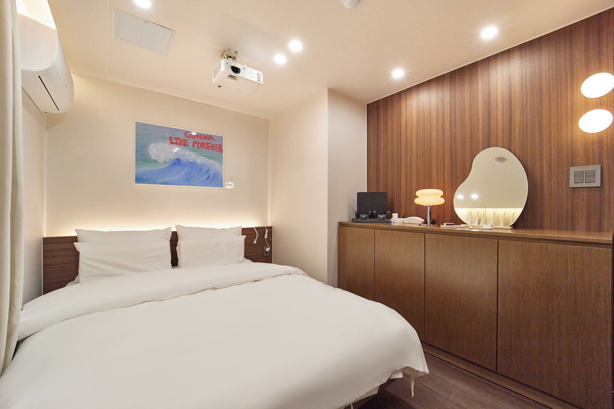 Una habitación de hotel con una cama grande, un armario de madera, un espejo y un cartel en la pared.