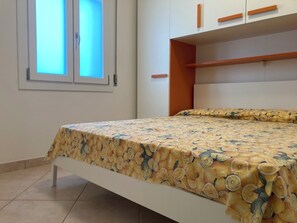 Ein Schlafzimmer mit Bett, Fenster und integrierten Regalen.