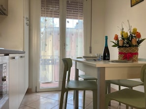En matplats med ett bord, stolar, en vas med blommor och en flaska.