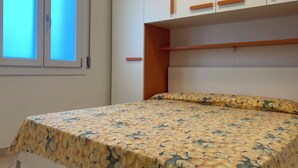 A bedroom with a bed, a window, and a wardrobe. - Cozy Apartment Close to the Beach (Rosolina)