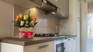 A modern kitchen with a built-in oven, stainless steel appliances, and a decorative vase with flowers on the counter. - Cozy Apartment Close to the Beach (Rosolina)
