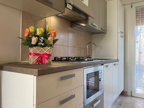 Eine moderne Küche mit Einbauofen, Edelstahlgeräten und einer Dekovase mit Blumen auf der Arbeitsfläche.