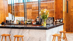 A bar area with a marble countertop, wooden stools, and a variety of bottles. - Urban by CityBlue Hotel, Dar es Salaam (Dar es Salaam)