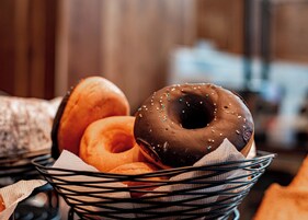 A basket containing various donuts, including chocolate and glazed varieties.