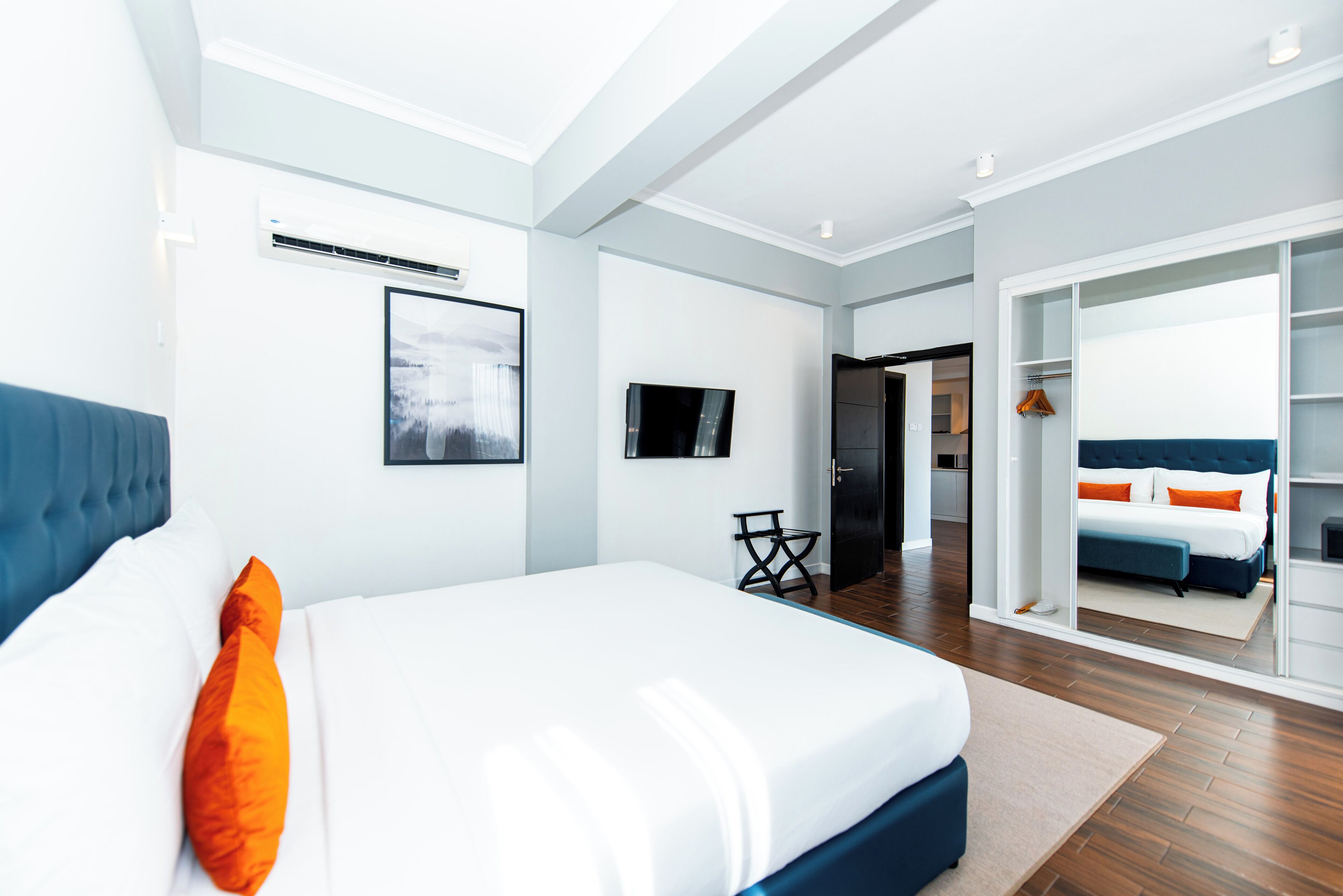 A modern hotel room with a large bed, a desk, and a wardrobe.