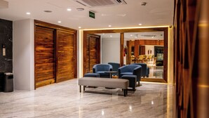 A lobby with a marble floor, wooden doors, and blue seating area. - Urban by CityBlue Hotel, Dar es Salaam (Dar es Salaam)
