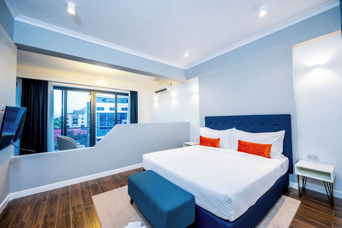Ett modernt hotellrum med en stor säng, en platt-TV och en balkong med utsikt över staden.