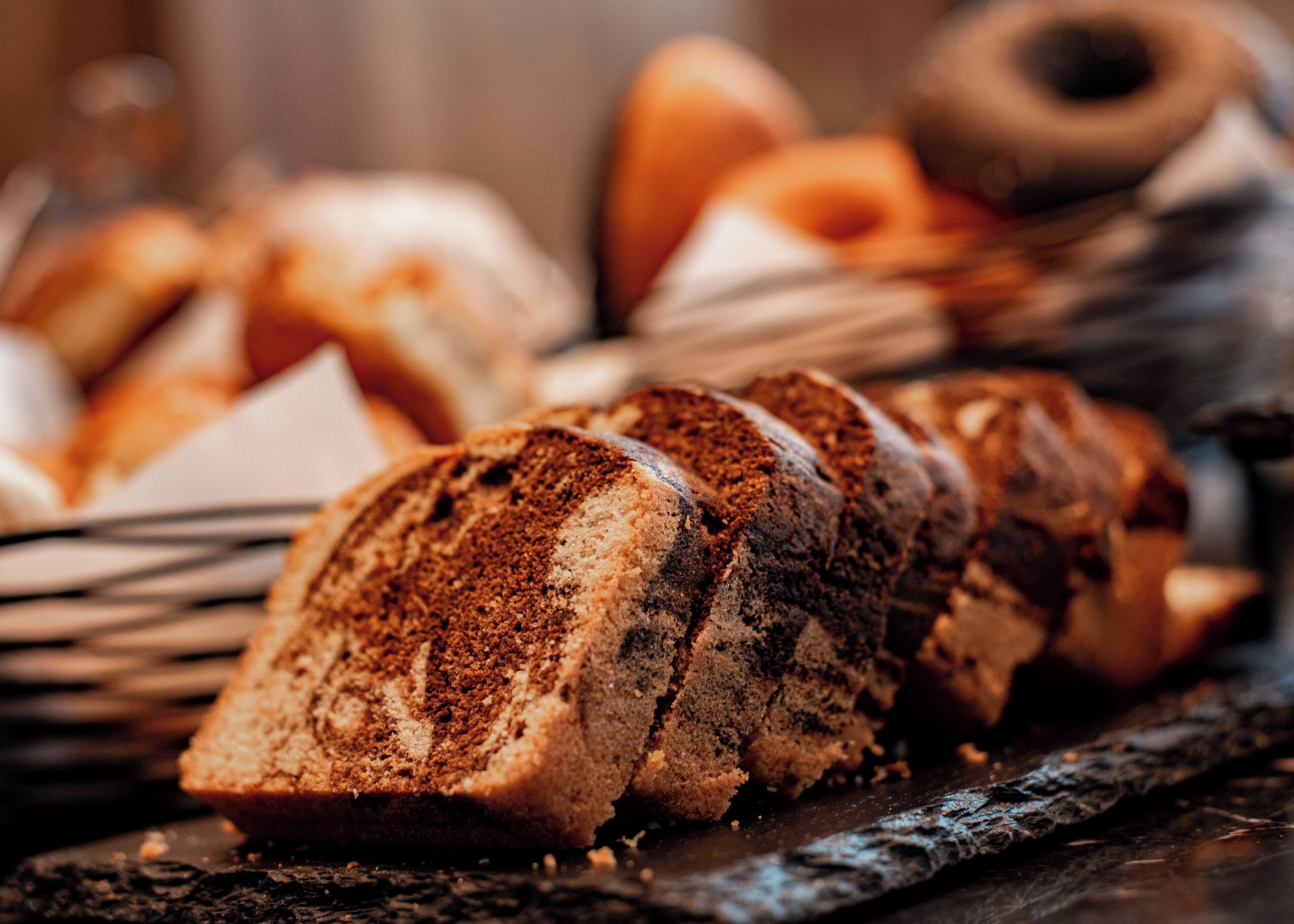 A close-up of sliced bread with a dark crust, possibly a type of rye or whole grain bread, on a dark surface.