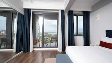Una habitación de hotel moderna con una cama grande, un balcón con vistas y un ventanal corredera.