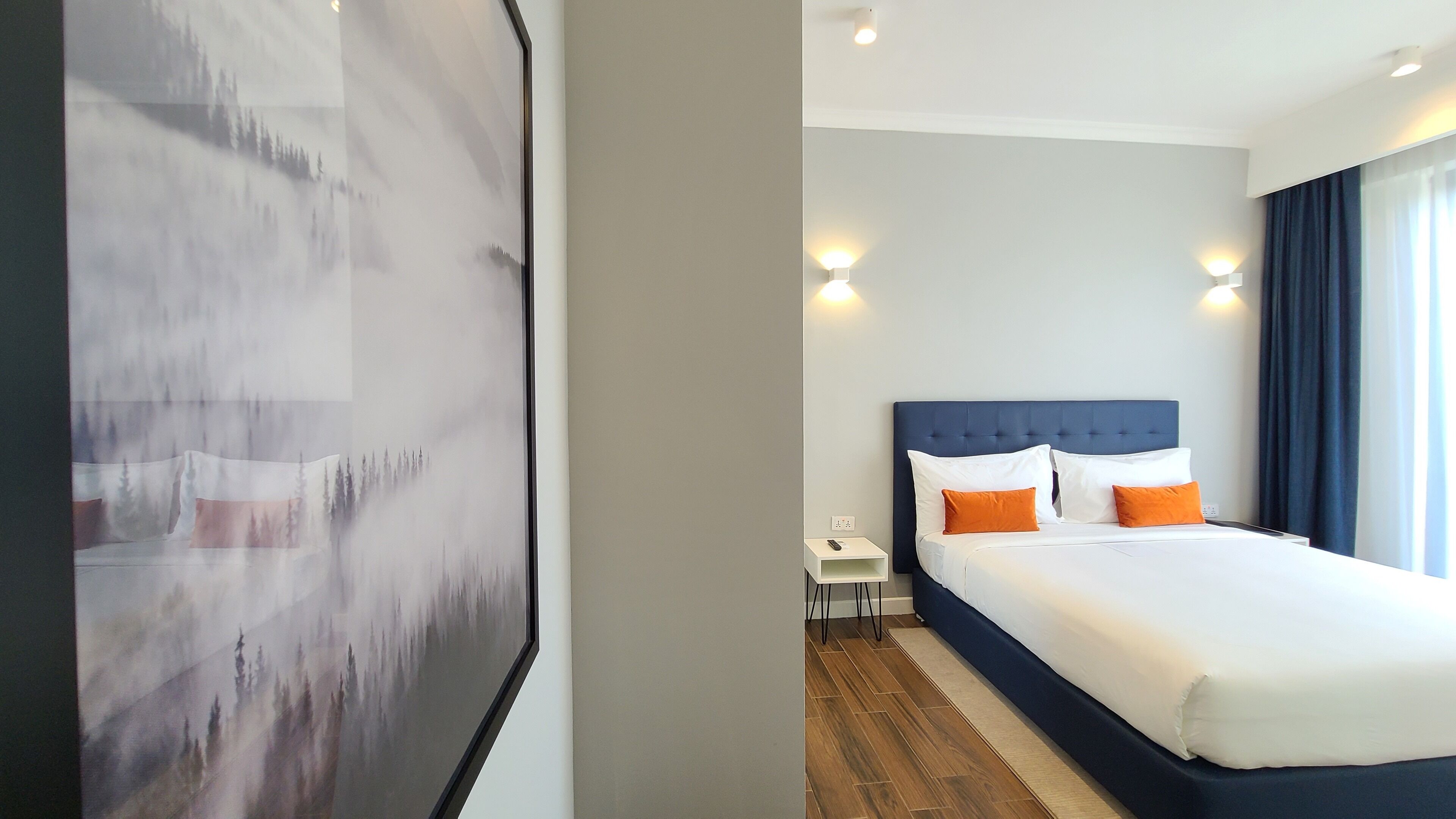 Une chambre d’hôtel avec un grand lit, une table de chevet et un luminaire fixé au mur.