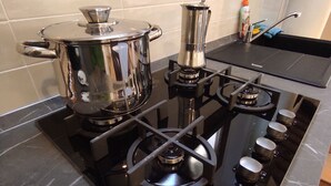 Une cuisine équipée d’une cuisinière, de casseroles et d’une bouteille de liquide vaisselle.