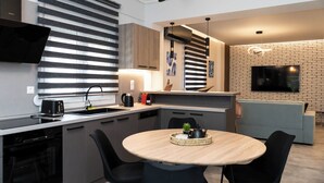 Una cocina moderna con comedor, horno empotrado y televisor de pantalla plana montado en la pared.