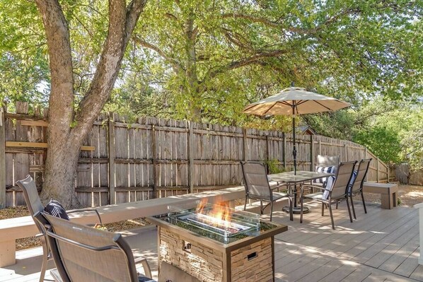 An outdoor patio with a fire pit, seating, and a wooden fence.