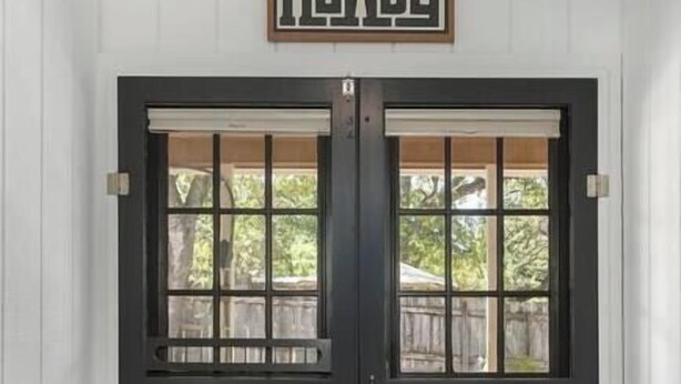 A dark wooden double door with glass panels and a decorative rug in front. - Revins Haus - Fire Pit & Walk to Main St (Fredericksburg)