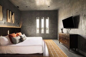 Un dormitorio moderno con una cama, un televisor montado en la pared y un amplio ventanal.