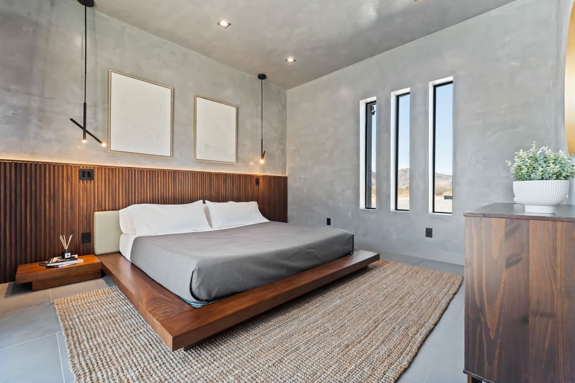 A modern bedroom with a bed, bedside tables, a wooden headboard, and a large window.