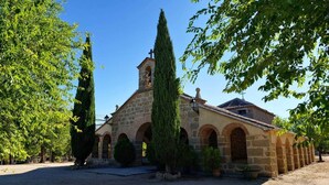 Une église en pierre dotée d’un clocher, entourée d’arbres et bordée d’une cour recouverte de gravier.