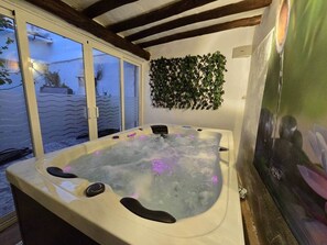 A hot tub with a view of the sea through a glass door, surrounded by wooden beams and a wall-mounted plant. - Tinguaton 1 (Aldeanueva de Barbarroya)