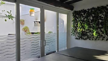 Een kamer met een schuifdeur, een betonnen bank en een aan de muur bevestigde plant.
