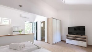 A modern hotel room with a bed, a TV, a wardrobe, and a bathroom visible through an open door. - Private villa Iko with swimming pool and view on mountain Biokovo (Zadvarje)