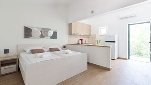A modern bedroom with a large bed, a small kitchenette, and a view of greenery. - Private villa Iko with swimming pool and view on mountain Biokovo (Zadvarje)