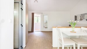 A modern kitchen with white cabinetry, a dining area with a white table and chairs, and a view of the outdoors through a glass door. - Private villa Iko with swimming pool and view on mountain Biokovo (Zadvarje)