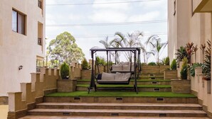 Eine Treppe führt ins Freie zu einem Gartenbereich mit einer Schaukel und einer Pergola.