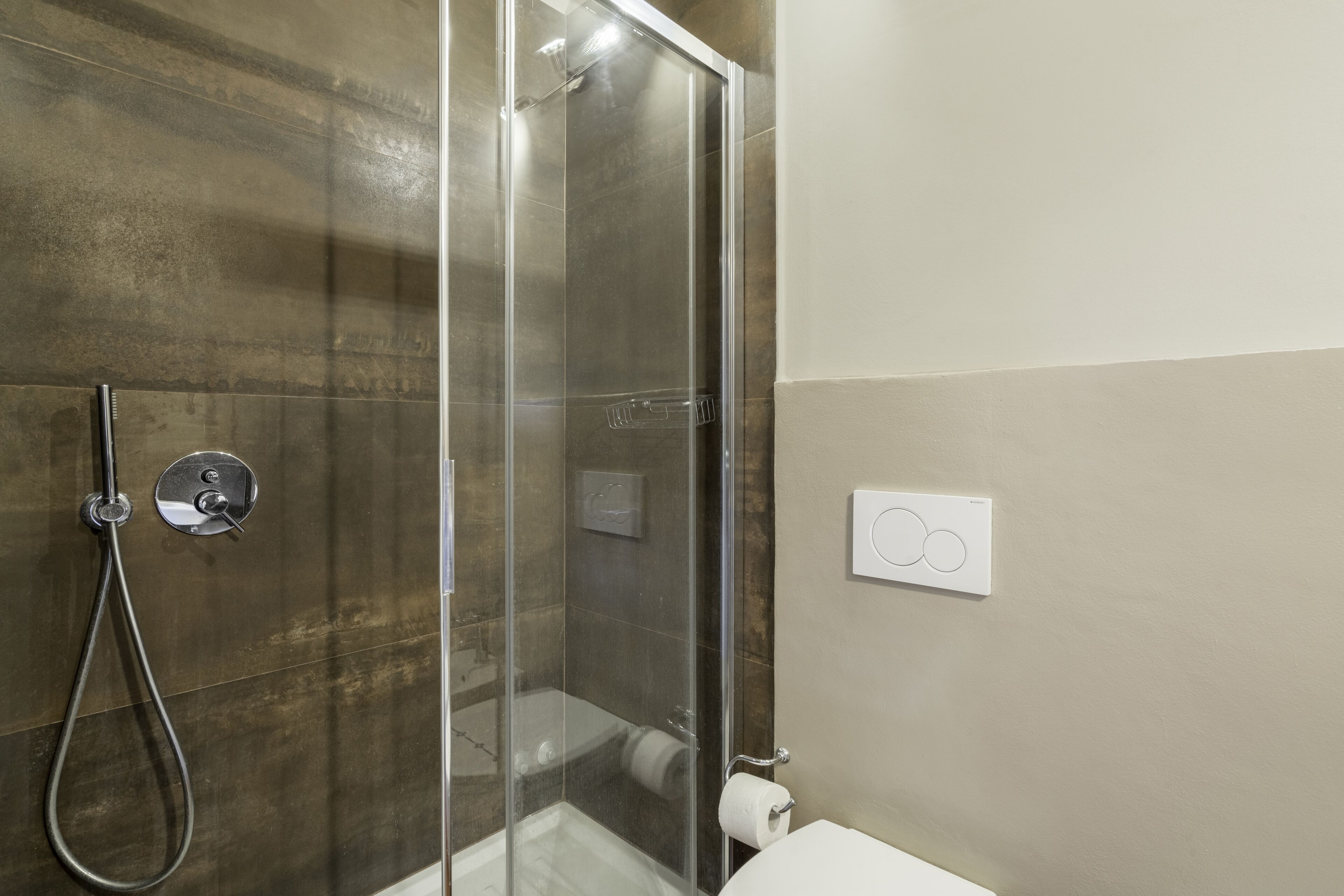 A bathroom with a glass-enclosed shower, a toilet, and a towel rack.